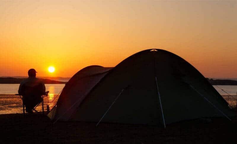 Orange sunset with camper and tent