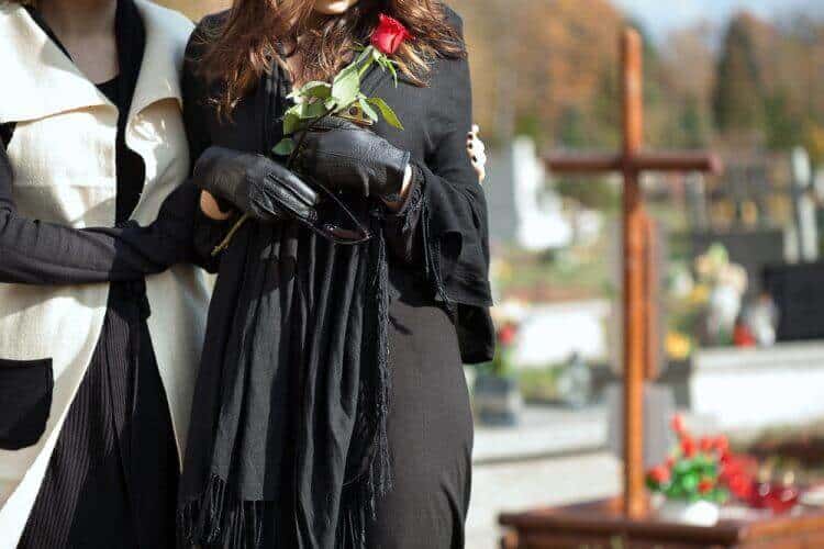 Mother holding her daughter standing above grave of family member