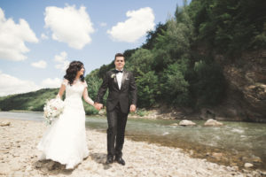 Elegant Gentle Stylish Groom And Bride Near River With Stones. Wedding Couple In Love - How to Avoid Kids While on Vacation in Hawaii