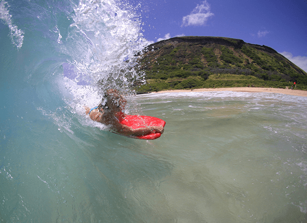The Definitive Guide to Visiting Hawaii - girl body surfing on sandys beach on oahu